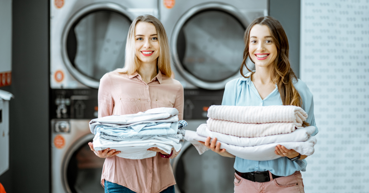 Women holding a stack of clothes Description automatically generated